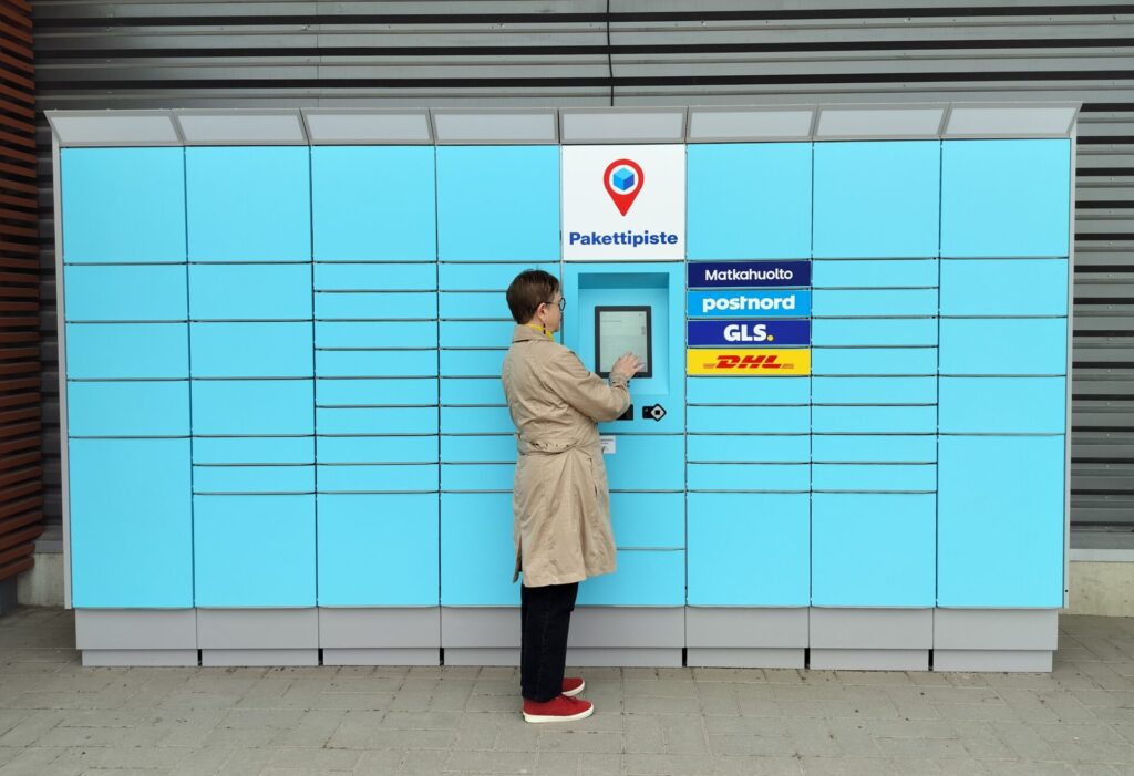 woman standing next to a Pakettipiste parcel locker